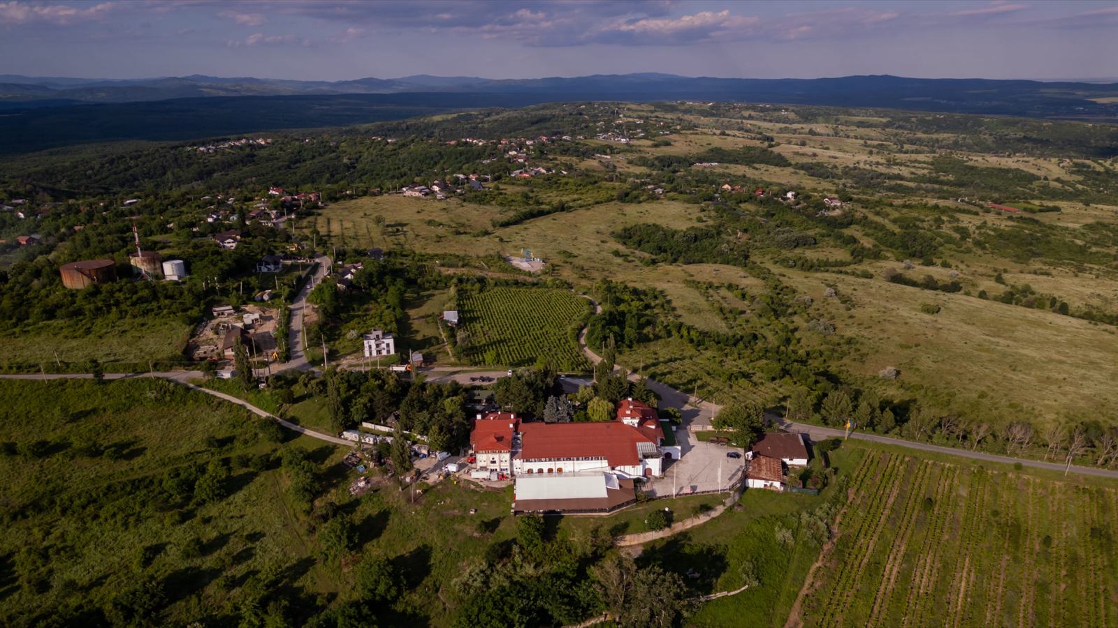 Casa Seciu văzută din aer: acoperișurile roșii pe deal, cu câmpia în depărtare
