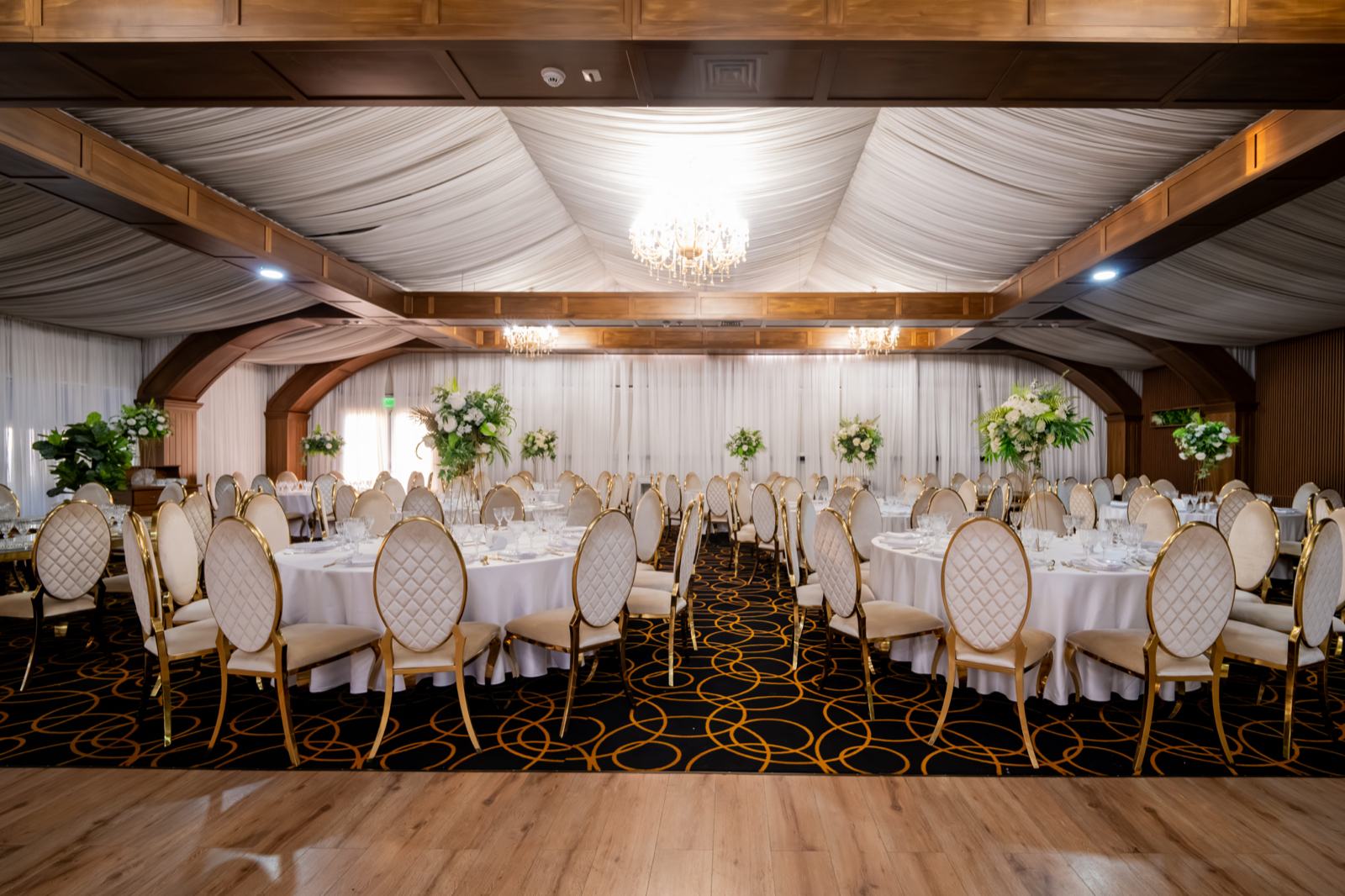 Sala mare aranjată, cu mese rotunde, grinzi de lemn și ring de dans