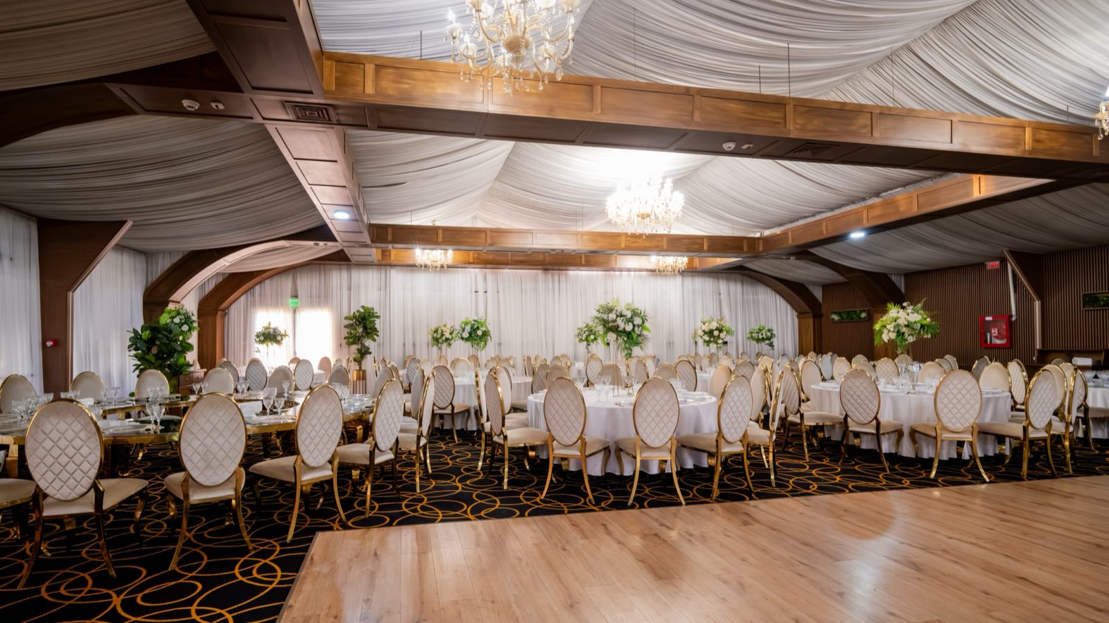 Sala mare aranjată, cu mese rotunde, grinzi de lemn și ring de dans