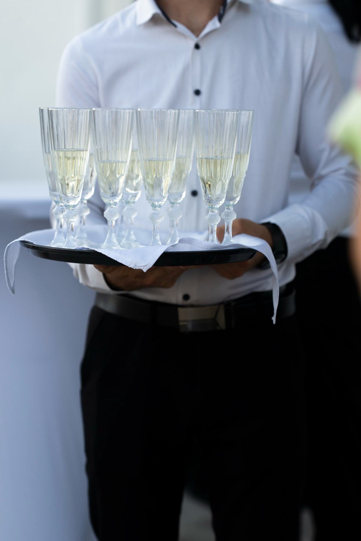 Ospătar cu o tavă de pahare cu vin spumant, pregătit pentru primirea invitaților