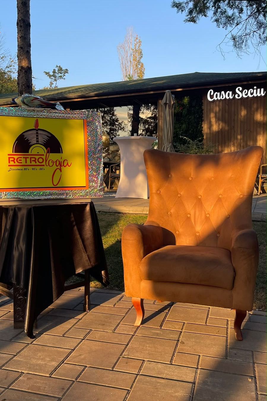 Fotoliu de catifea portocalie lângă firma Retrologia, în lumina de după-amiază