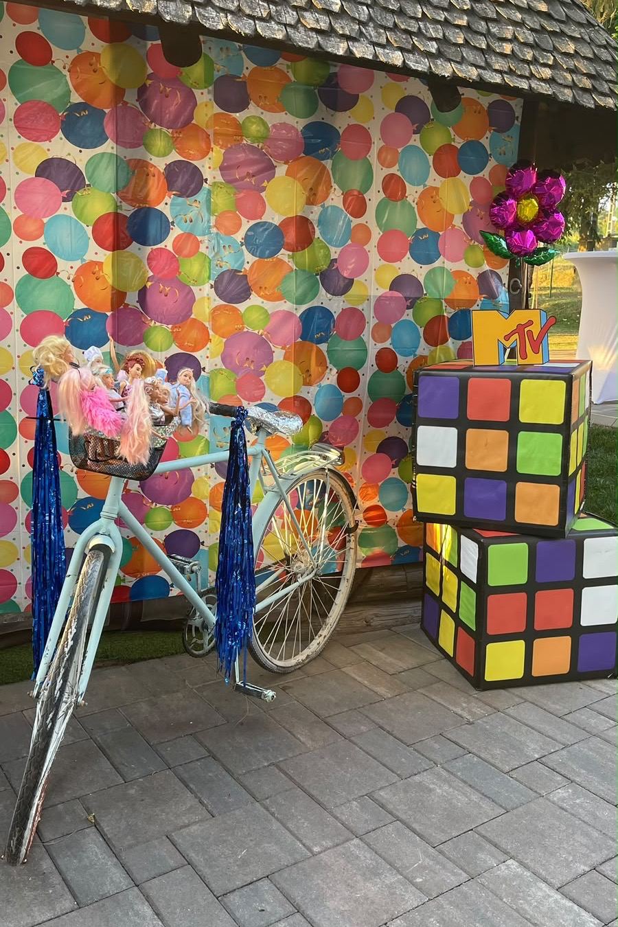 Colț de fotografiat: perete colorat cu buline, cuburi Rubik uriașe și o bicicletă albastră sprijinită