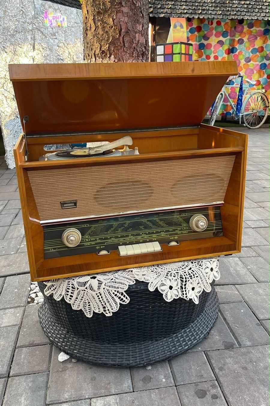 Pickup de epocă într-o casetă de lemn, cu capacul ridicat și un disc pe platan, pe un covoraș de dantelă