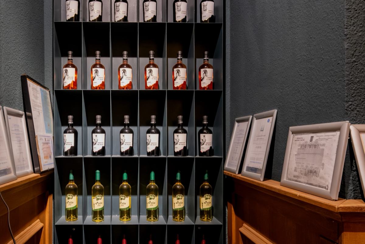 Rafturi cu sticle de vin Casa Seciu, așezate pe sortimente